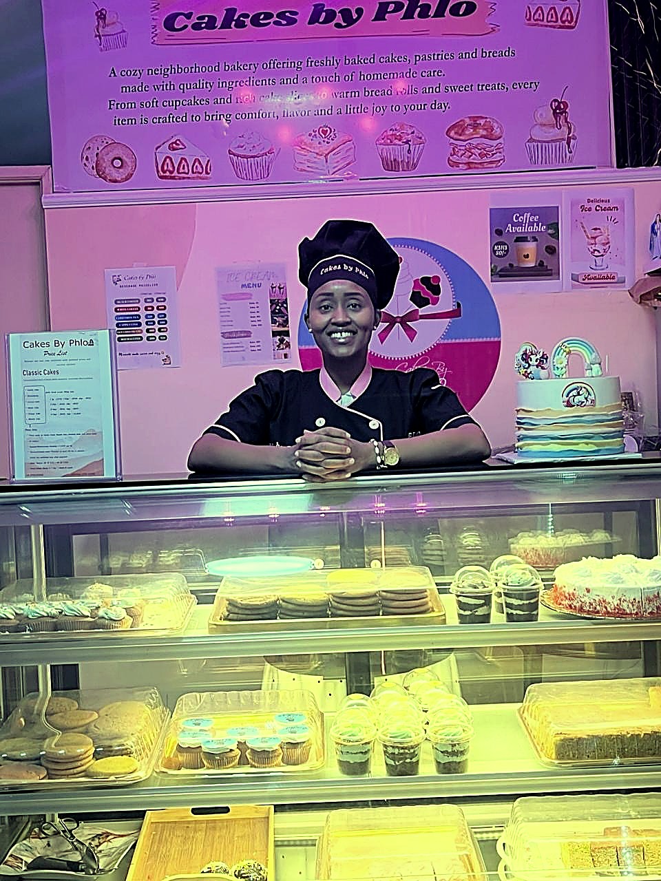 Phlo posed behind the display case with fresh desserts and cakes